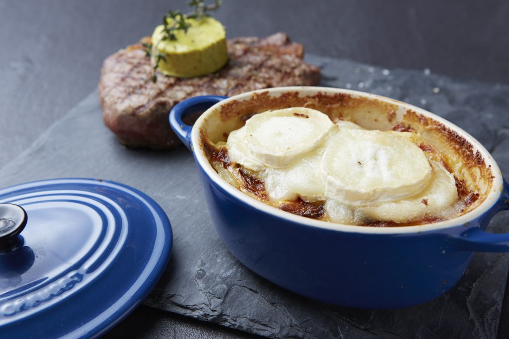 Überbackenes Kartoffelgratin an gegrilltem Steak „Café de Paris“